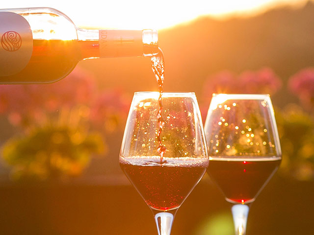 Red wine being poured into glasses at sunset